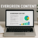 Laptop auf Schreibtisch mit geöffneter Seite „Evergreen Content“, daneben Notizbuch und Pflanze.